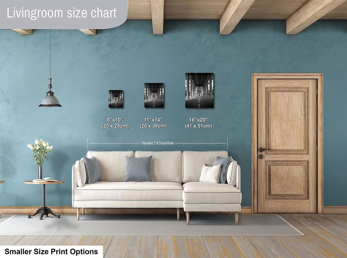 a living room with a white sofa, a wooden door, and a hanging light fixture. There are three framed black and white photographs of cityscapes displayed on the wall, each with a different size and height. The wall is painted in a light blue color, and the floor is covered with a gray rug.