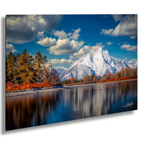 a serene landscape with a snow-capped mountain range reflected in a calm lake, surrounded by trees with autumn foliage.