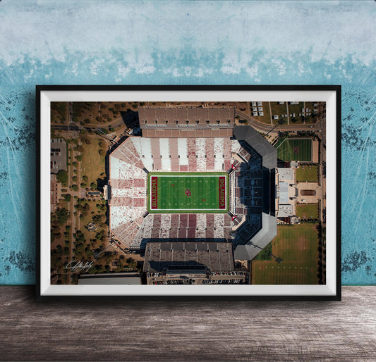The image is an aerial view of a football stadium with a green field and surrounding buildings.
