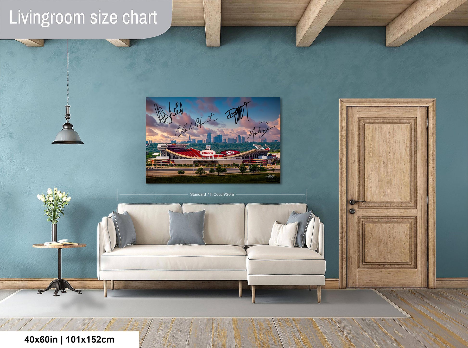 a living room with a large wall-mounted poster of a stadium, a white sofa, a wooden door, and a small table with a vase of flowers.