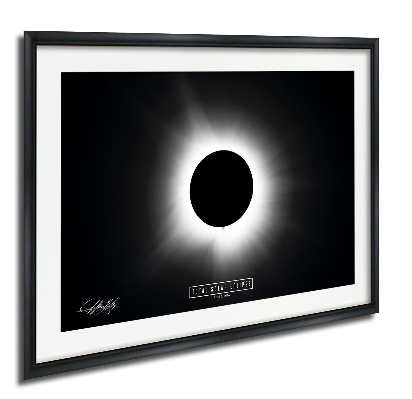 The image is a framed photograph depicting a total solar eclipse, with the moon completely obscuring the sun and creating a bright, white ring around it.