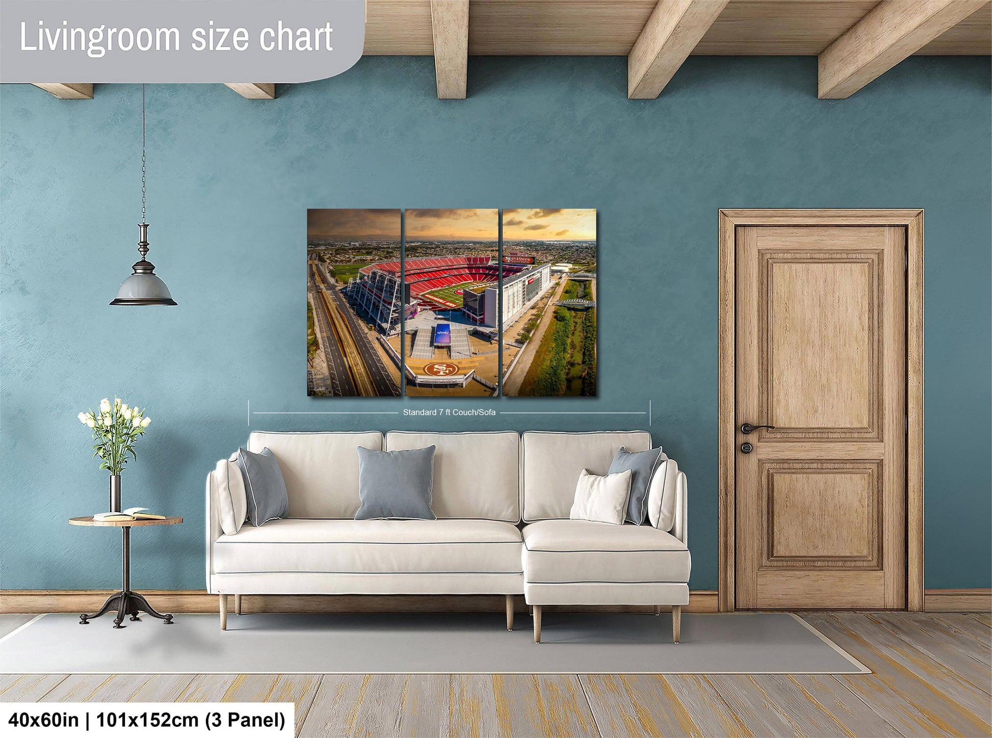 The image is a living room with a large white sofa, a wooden door, and a painting of a stadium on the wall.
