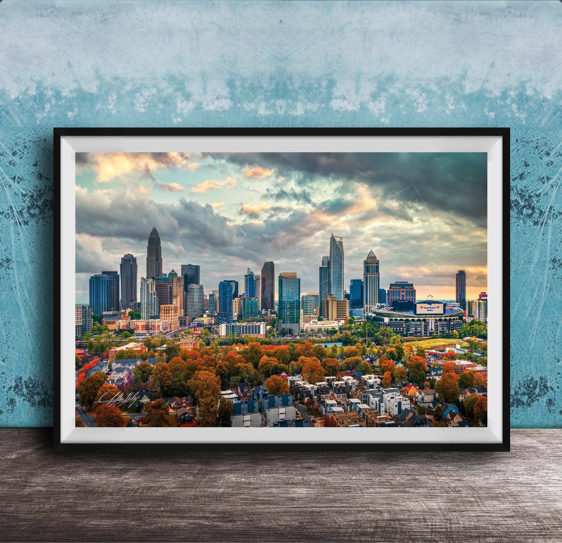 A framed aerial view of the skyline of a city, with tall buildings and skyscrapers against a cloudy sky.