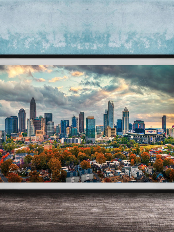 A framed aerial view of the skyline of a city, with tall buildings and skyscrapers against a cloudy sky.