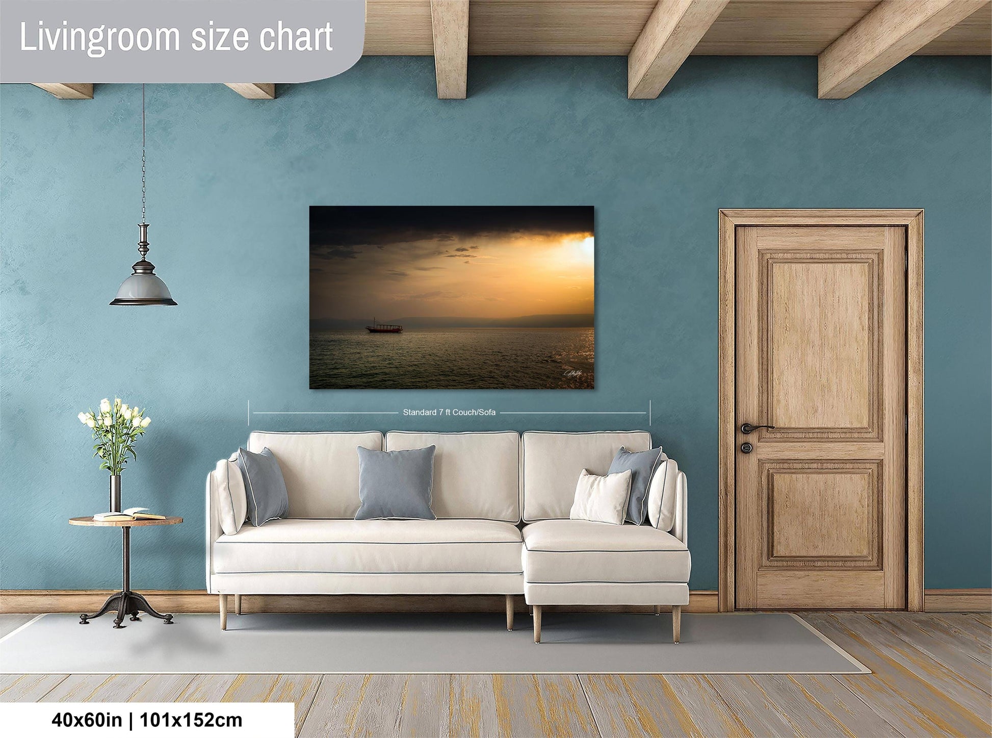 a living room with a large white sofa, a wooden door, and a painting of a sunset over the ocean hanging on the wall.