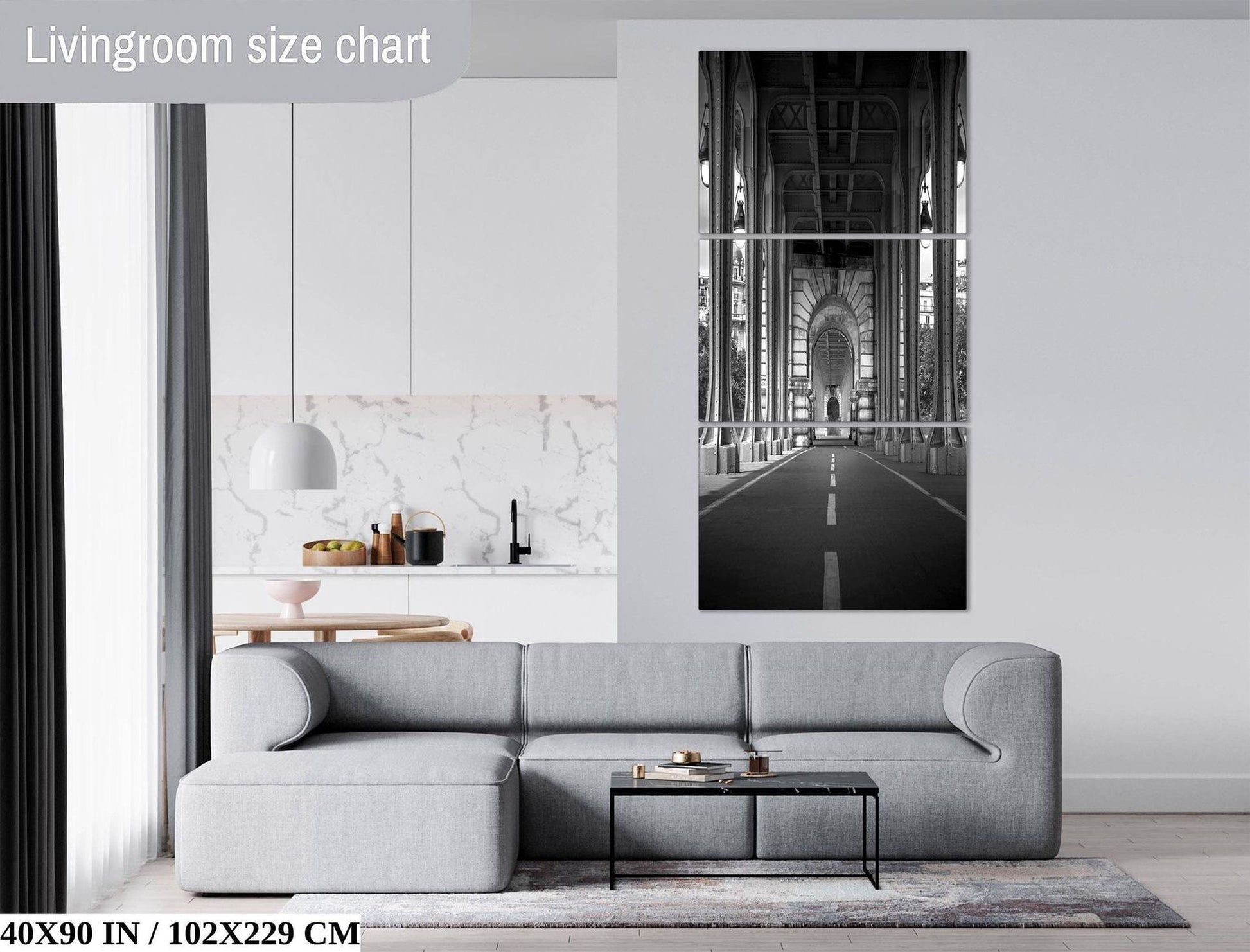 a modern living room with a gray sectional sofa, a glass coffee table, and a large black and white photograph of a bridge in the background.