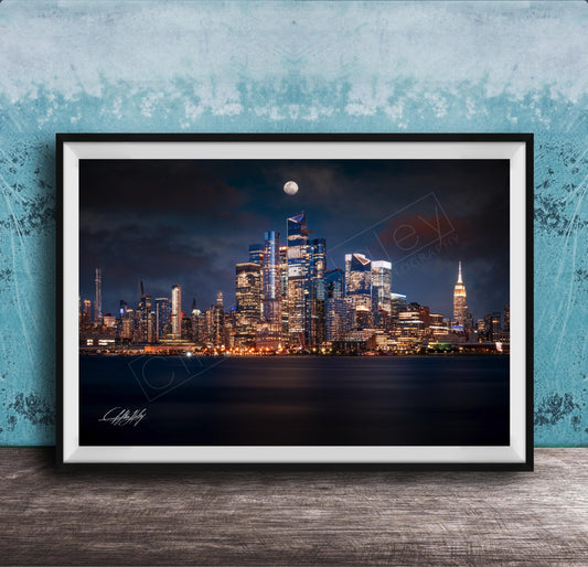 A framed photograph of the New York City skyline at night, with the city's iconic landmarks illuminated against a dark sky.