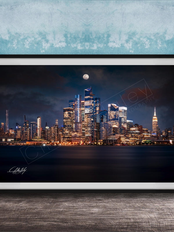 A framed photograph of the New York City skyline at night, with the city's iconic landmarks illuminated against a dark sky.