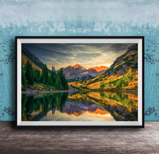 The image is a framed photograph depicting a serene mountain landscape with a lake reflecting the vibrant colors of the sunset.