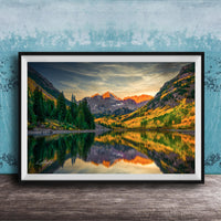 The image is a framed photograph depicting a serene mountain landscape with a lake reflecting the vibrant colors of the sunset.