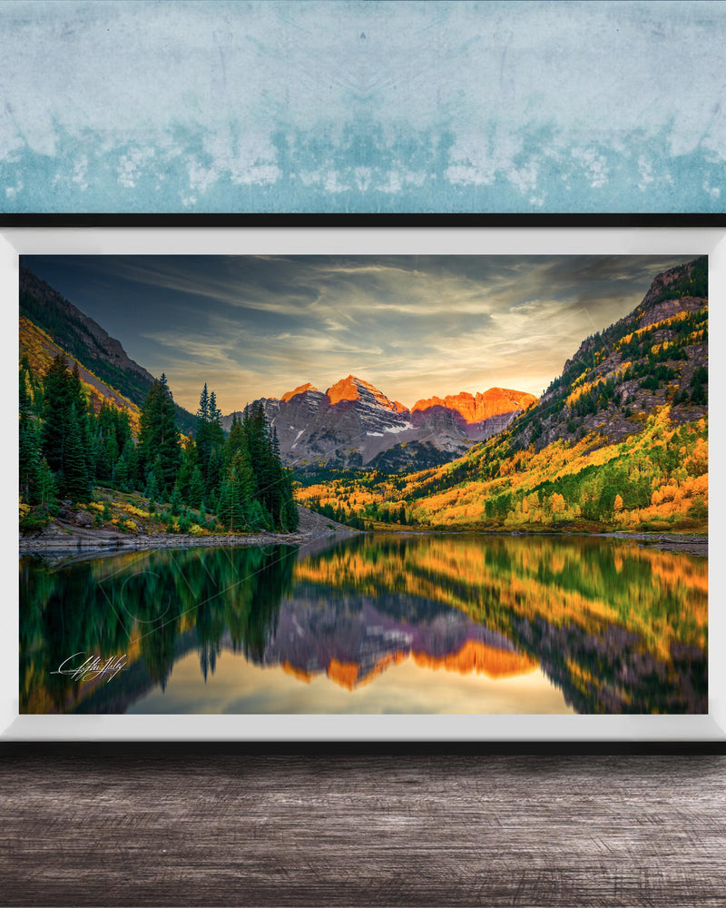 The image is a framed photograph depicting a serene mountain landscape with a lake reflecting the vibrant colors of the sunset.