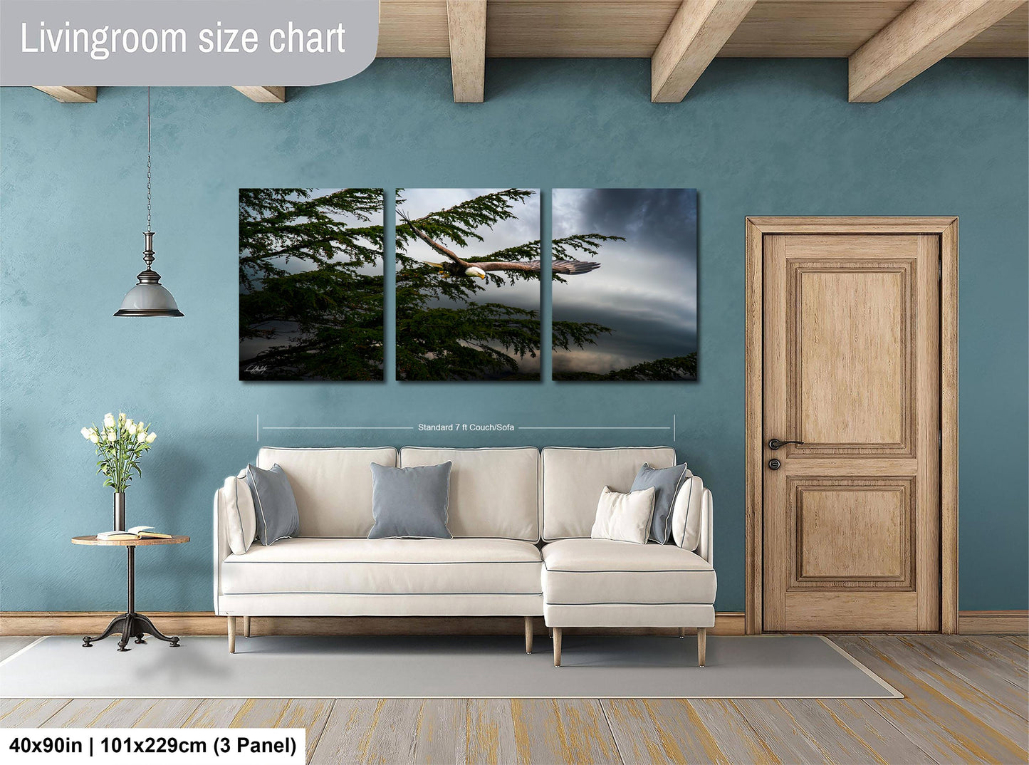 The image is a living room with a large white sofa, a wooden door, and a painting of a tree on the wall.