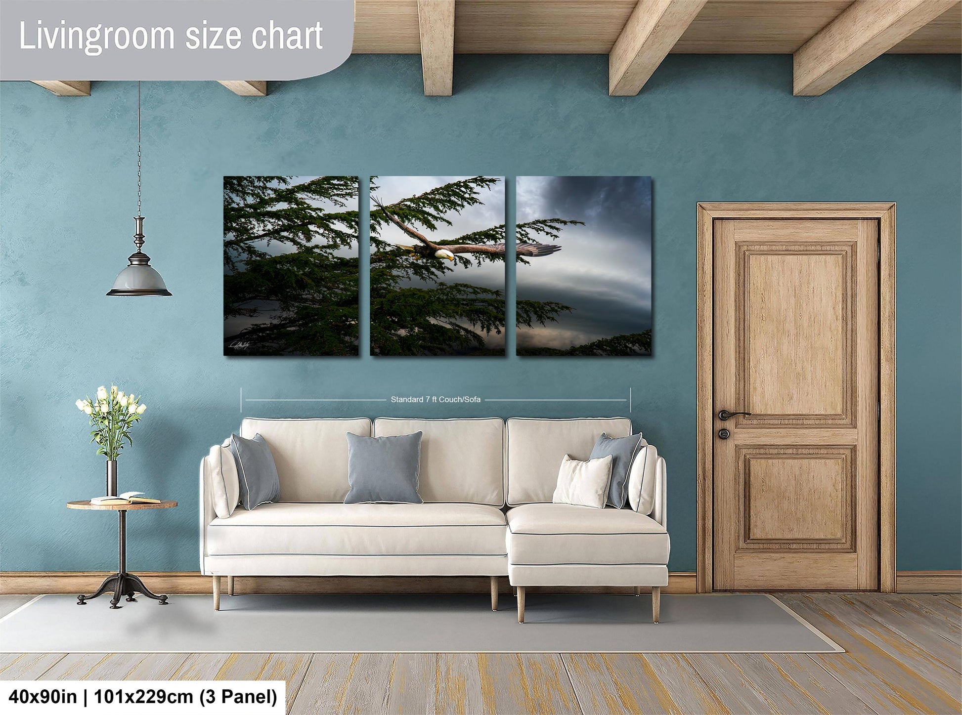 The image is a living room with a large white sofa, a wooden door, and a painting of a tree on the wall.
