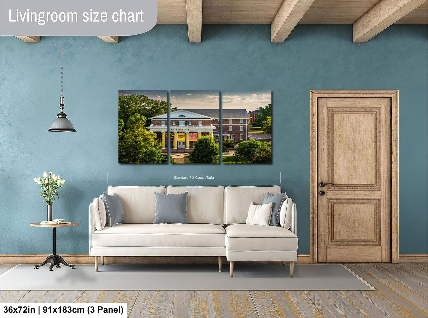 The image is a living room with a large white sofa, a wooden door, and a painting of a house on the wall.
