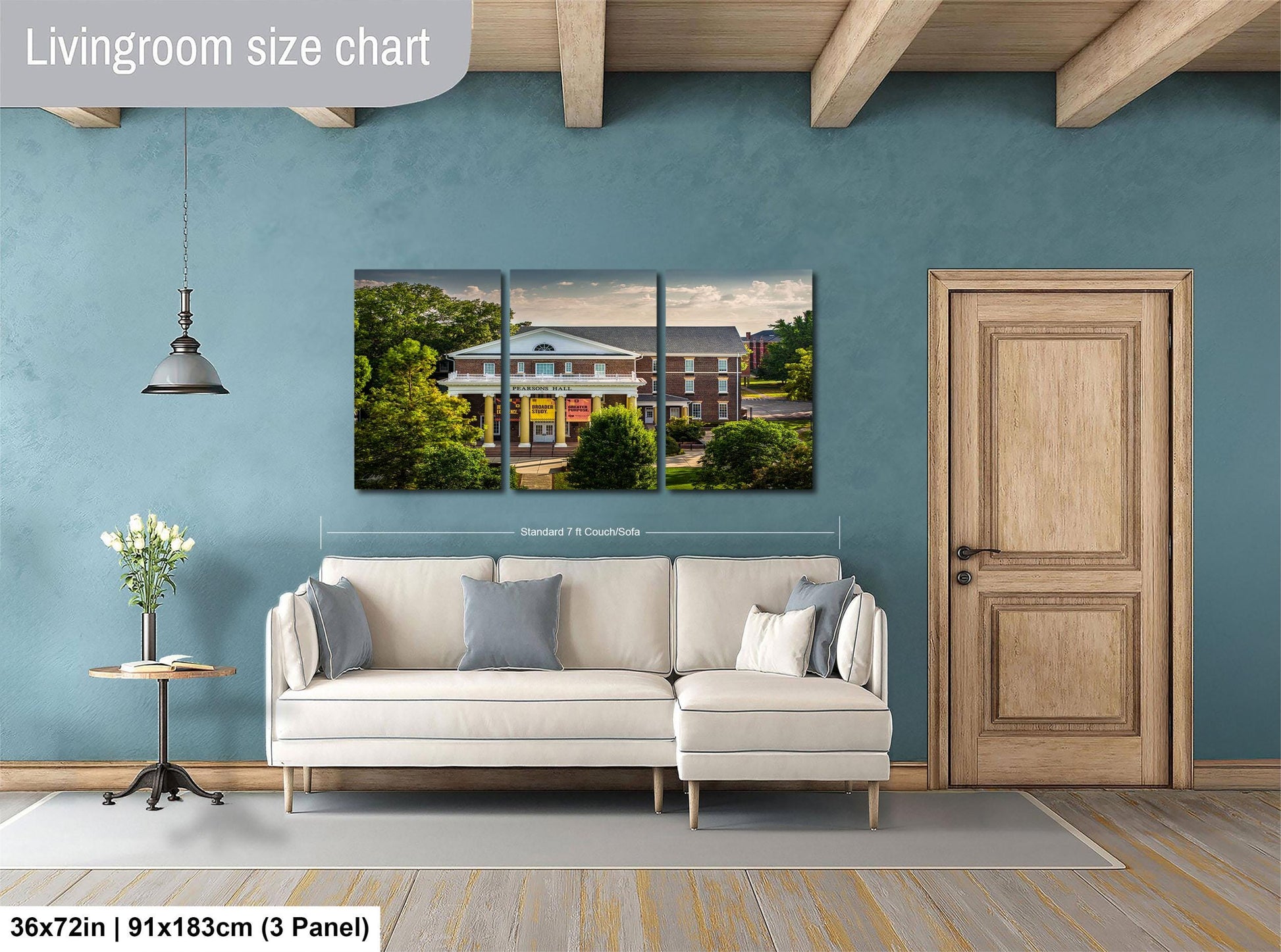 The image is a living room with a large white sofa, a wooden door, and a painting of a house on the wall.