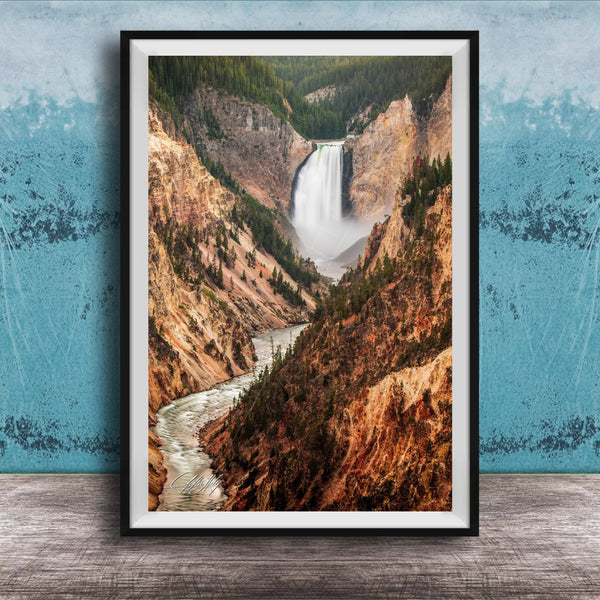 A framed photograph of a majestic waterfall cascading down a rugged, mountainous landscape.