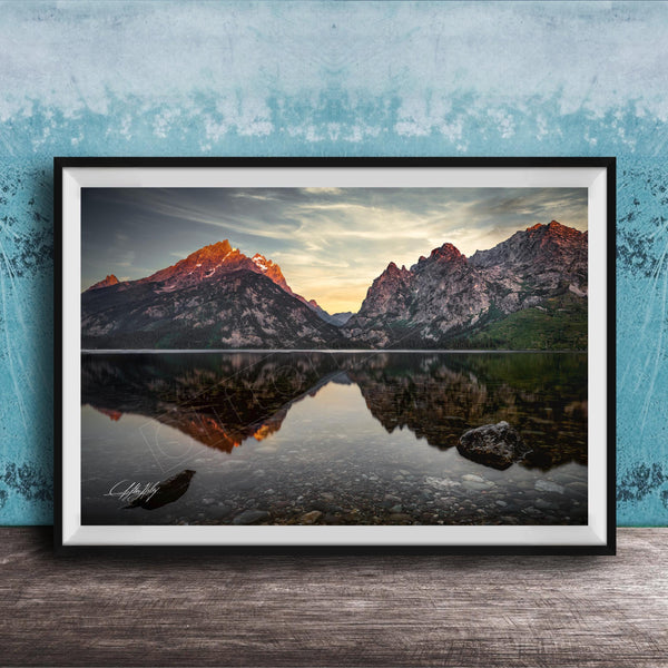 a serene mountain landscape with a calm lake reflecting the mountains and sky.