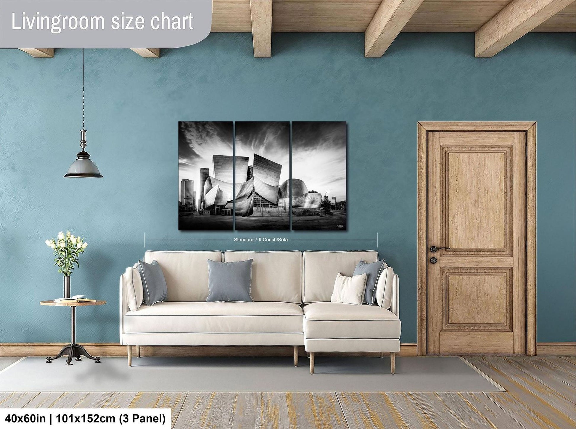 The image is a living room with a large white sofa, a wooden door, and a black and white photograph of a building on the wall.