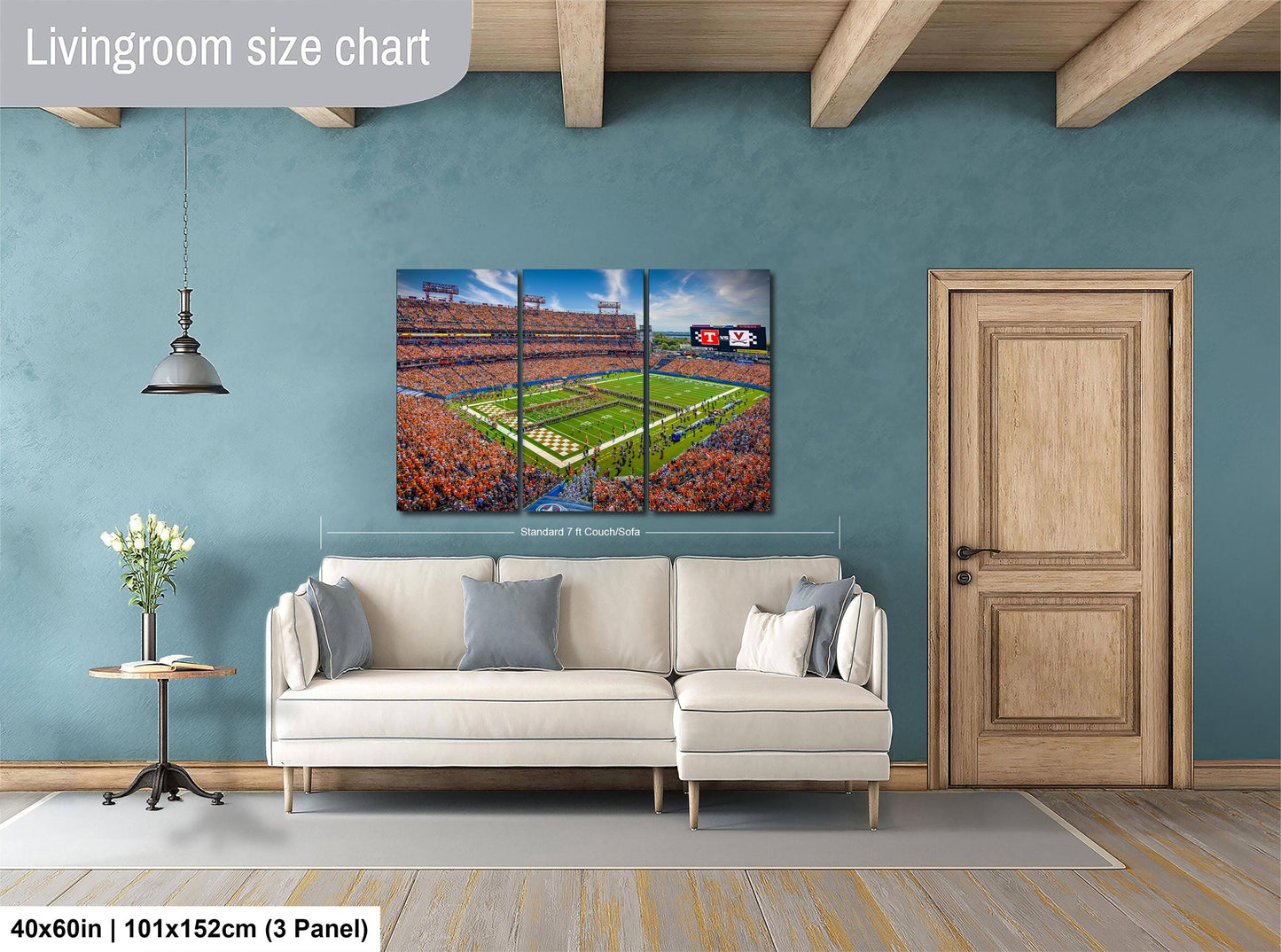 The image is a living room with a large wall-mounted painting depicting a football stadium. The painting is a collage of three panels, with the top and bottom panels showing the stadium and the middle panel showing the field. The painting is framed in a white frame and hangs above a white sofa.