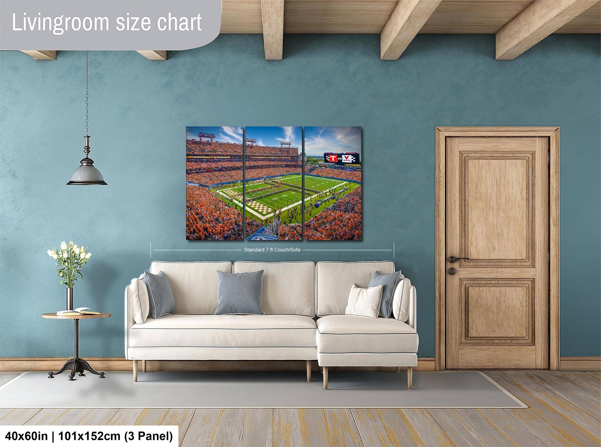 The image is a living room with a large wall-mounted painting depicting a football stadium. The painting is a collage of three panels, with the top and bottom panels showing the stadium and the middle panel showing the field. The painting is framed in a white frame and hangs above a white sofa.
