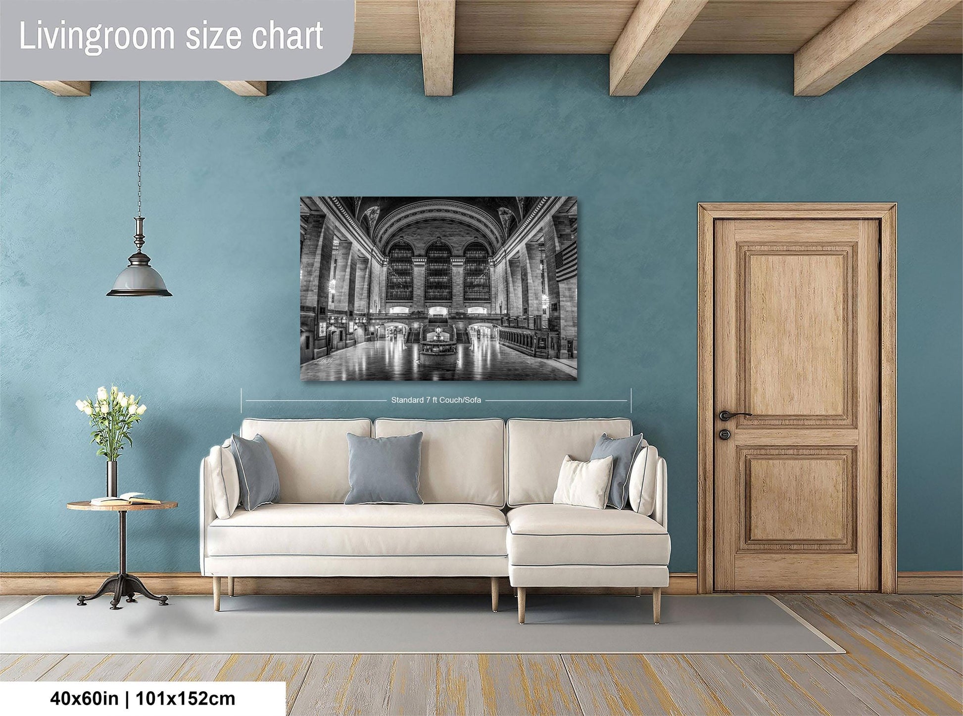 a living room with a large, black and white photograph of a grand, historic building hanging on the wall. The photograph is framed and measures 40 inches by 101.5 centimeters. The living room is furnished with a white sofa and a wooden door, creating a cozy and inviting atmosphere.