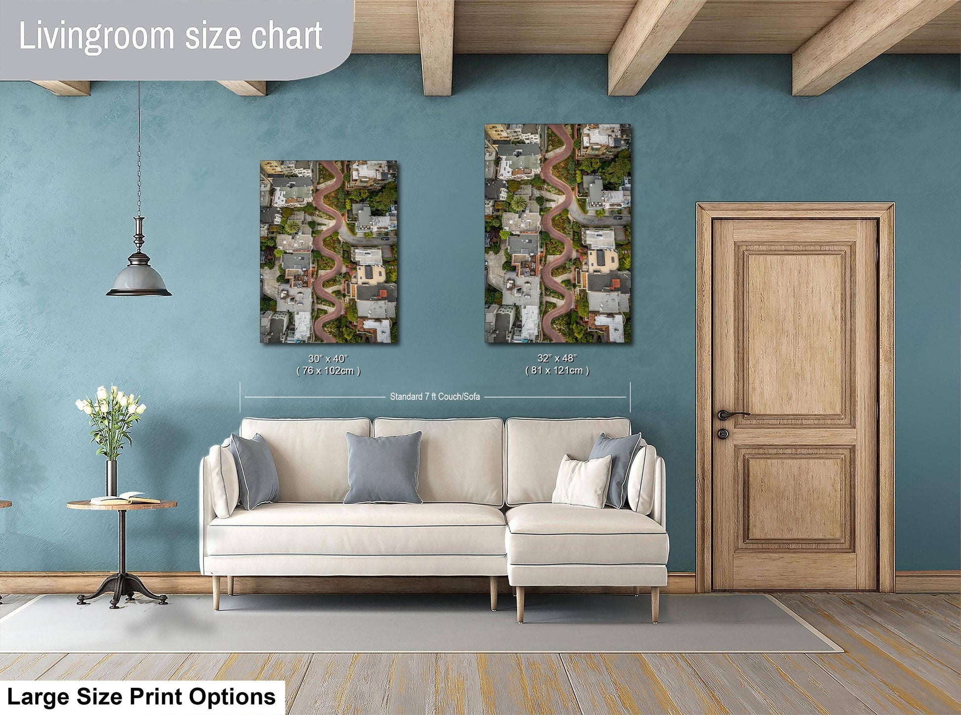 a living room with a white sofa, a wooden door, and two framed aerial photographs of a city street.