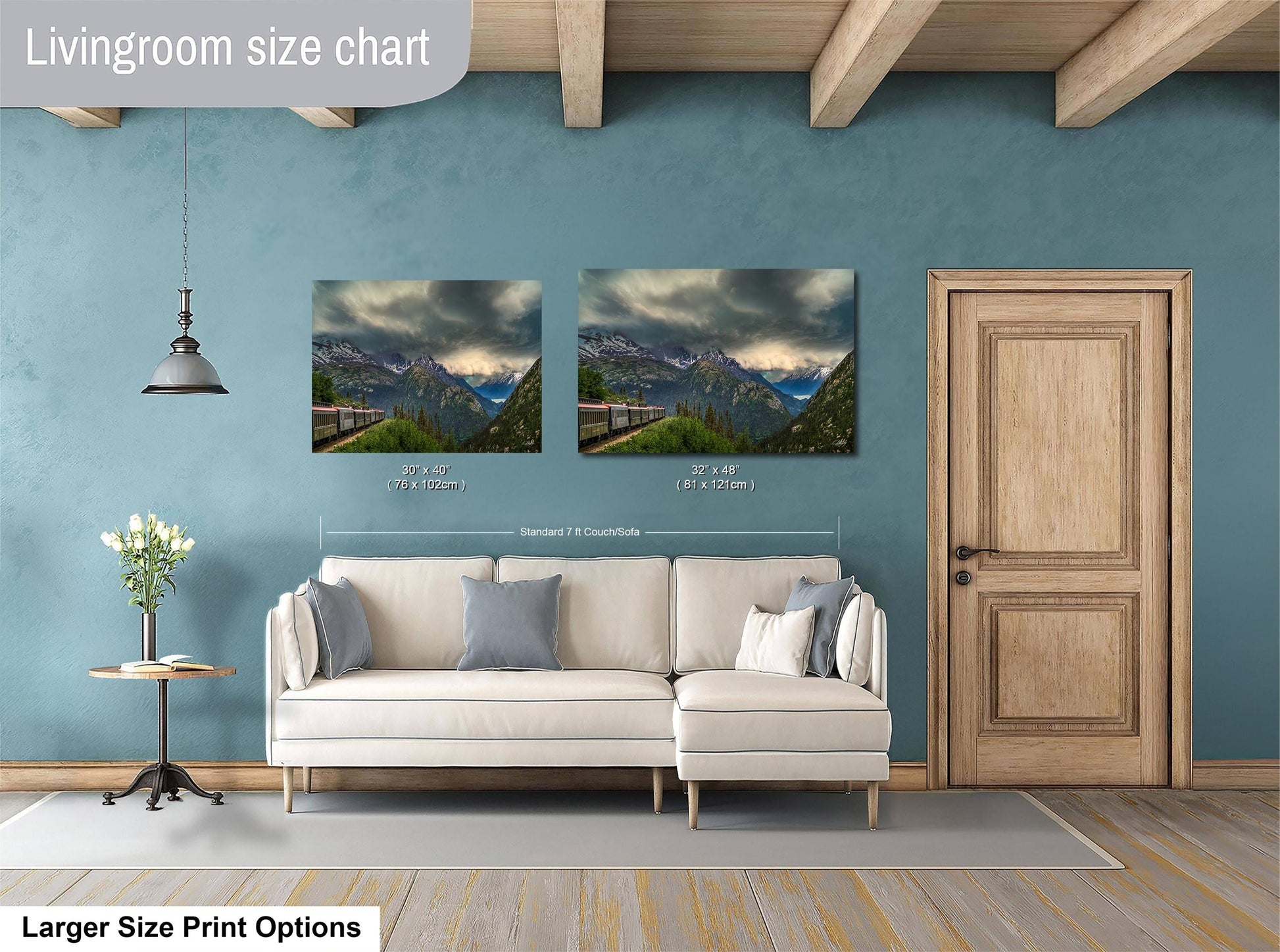 a living room with a white sofa and a wooden door. Above the sofa, there are two framed landscape paintings depicting mountains and a winding road. The paintings are of similar size, and the wall behind them is painted a light blue color.
