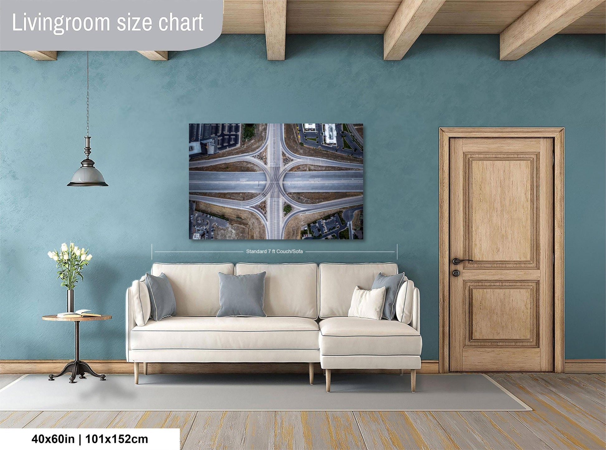 a living room with a large white sofa, a wooden door, and a large wall-mounted artwork depicting an aerial view of a highway intersection.