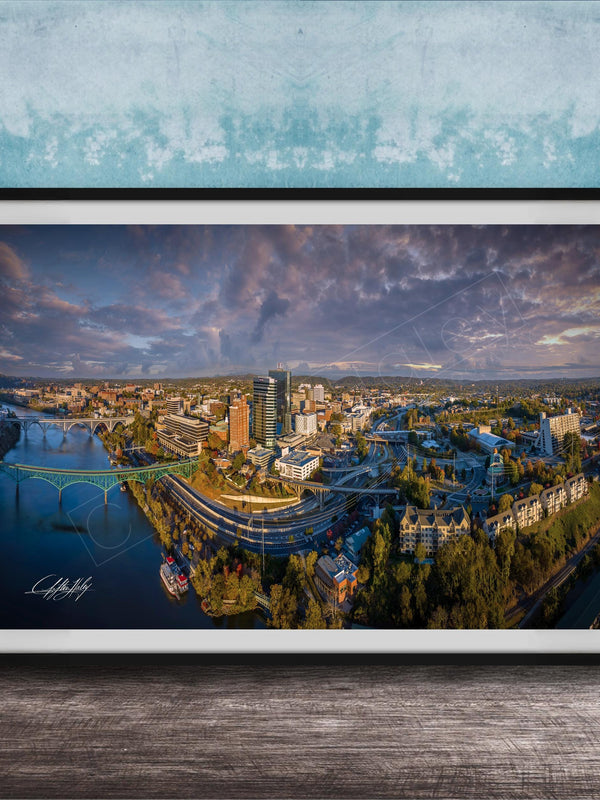 The image is a framed aerial view of a cityscape, showcasing a mix of buildings, roads, and a river.