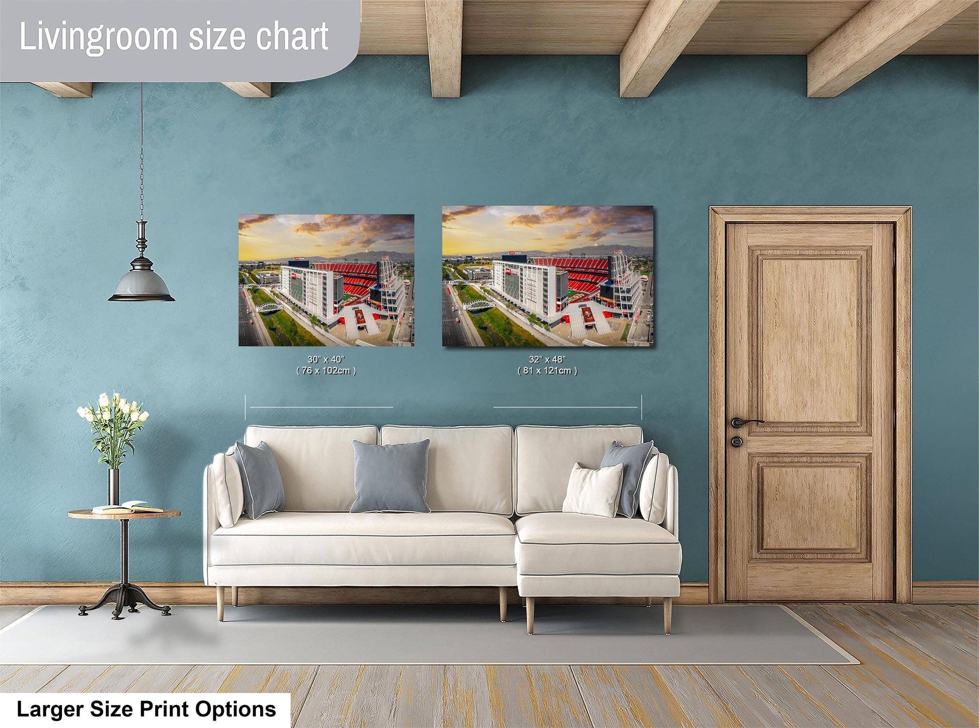 a living room with a white sofa and a wooden door. Above the sofa, there are two framed pictures of a building, likely a stadium. The living room has a blue wall and a wooden ceiling.