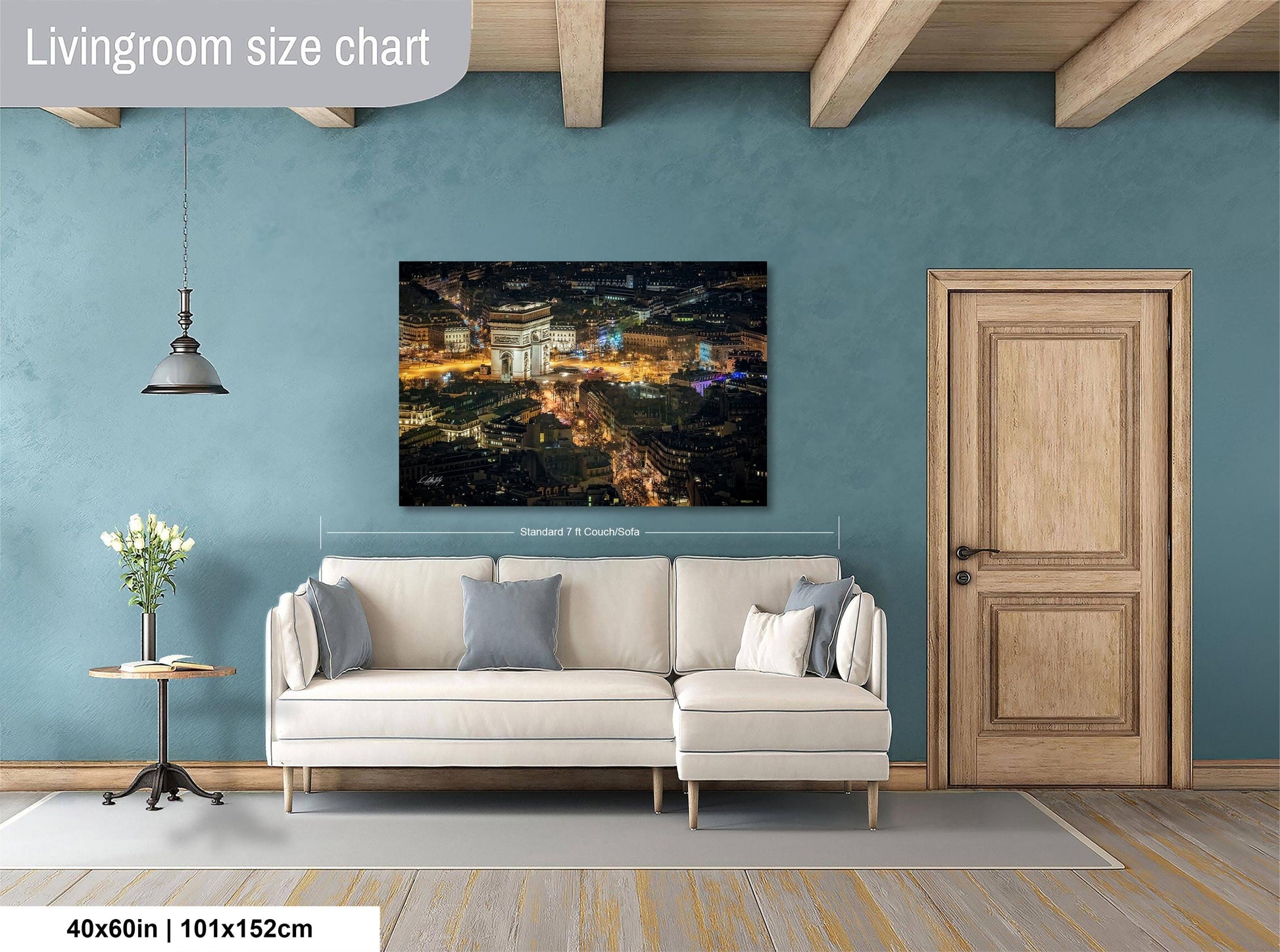 a living room with a large white sofa, a wooden door, and a painting of a cityscape hanging on the wall.
