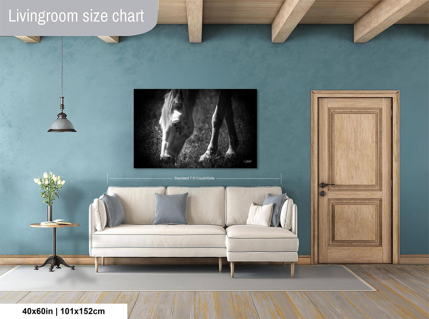 a living room with a large white sofa, a wooden door, and a black and white photograph of a horse's head on the wall.