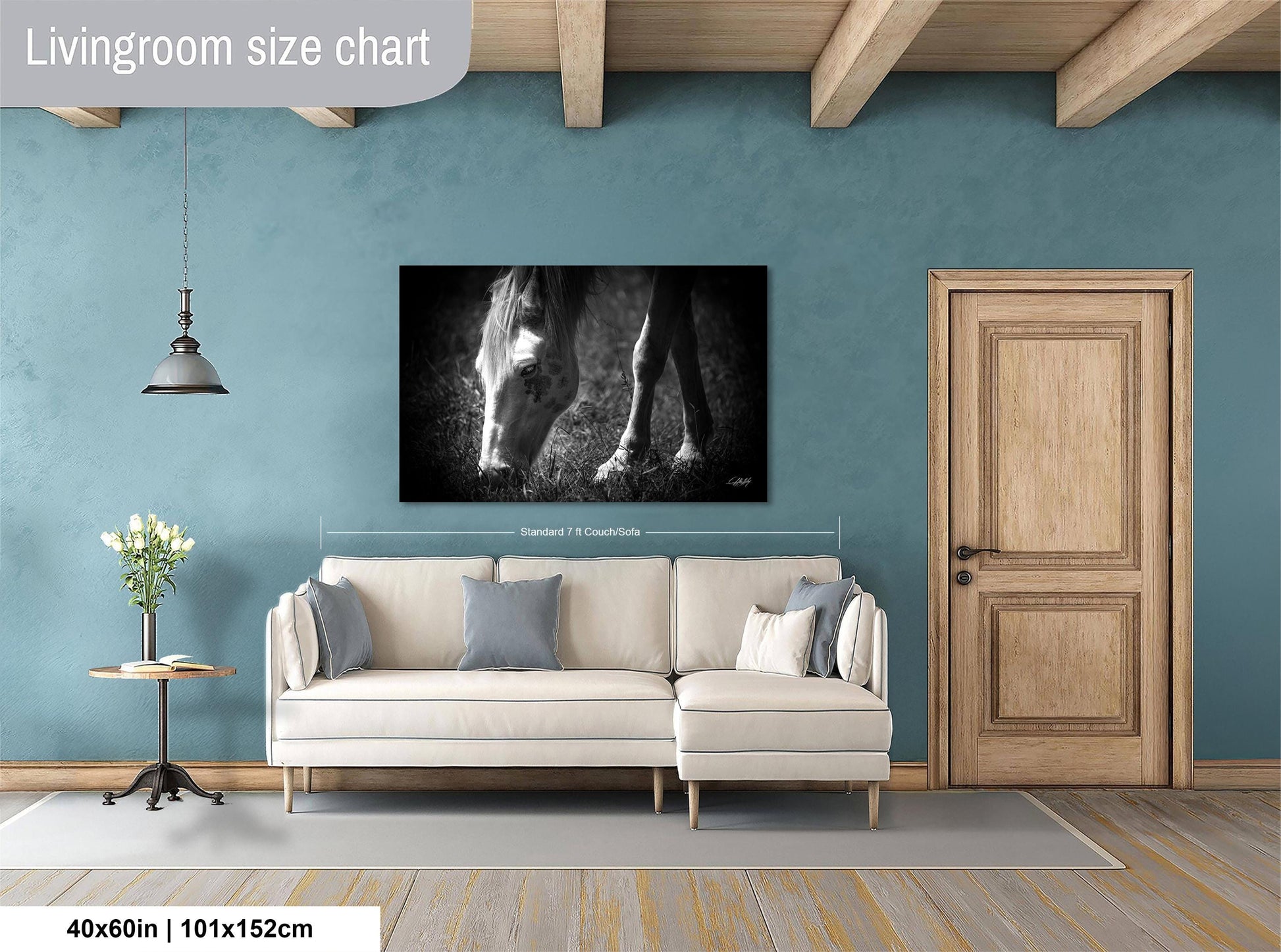 a living room with a large white sofa, a wooden door, and a black and white photograph of a horse's head on the wall.