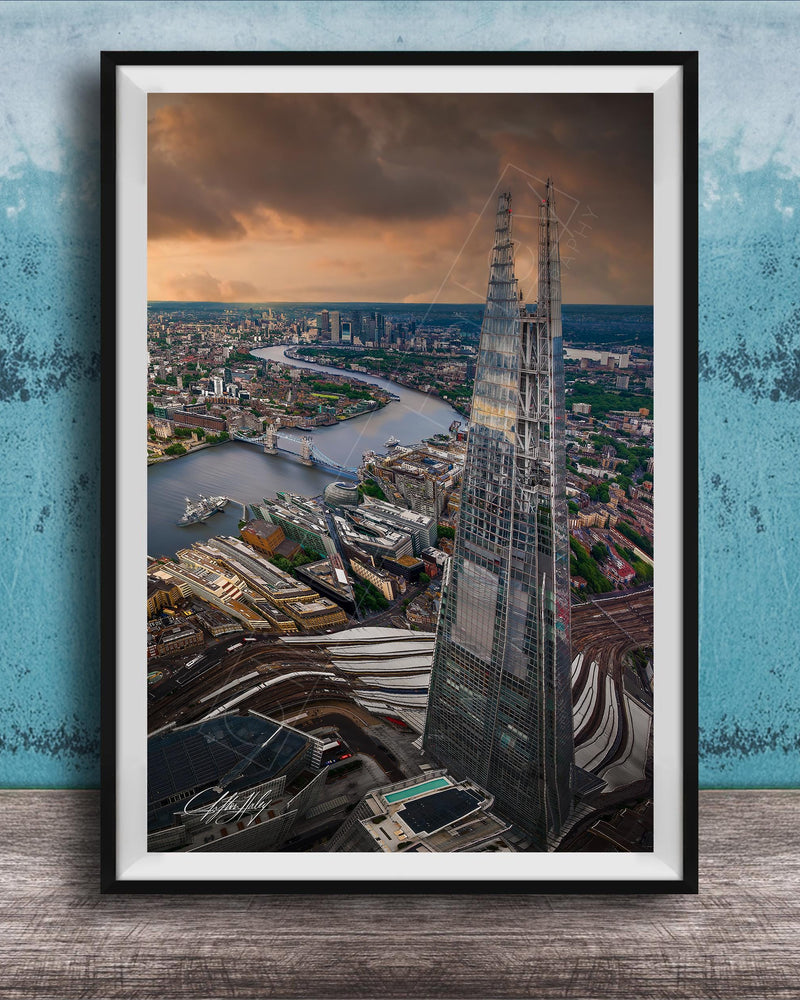 The image is a framed aerial view of the London skyline, showcasing the iconic Shard skyscraper and the River Thames in the background.
