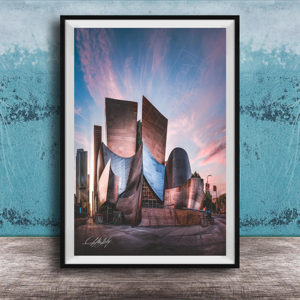 A framed photograph of a modern, curved building with a distinctive architectural design, set against a colorful sky at sunset.