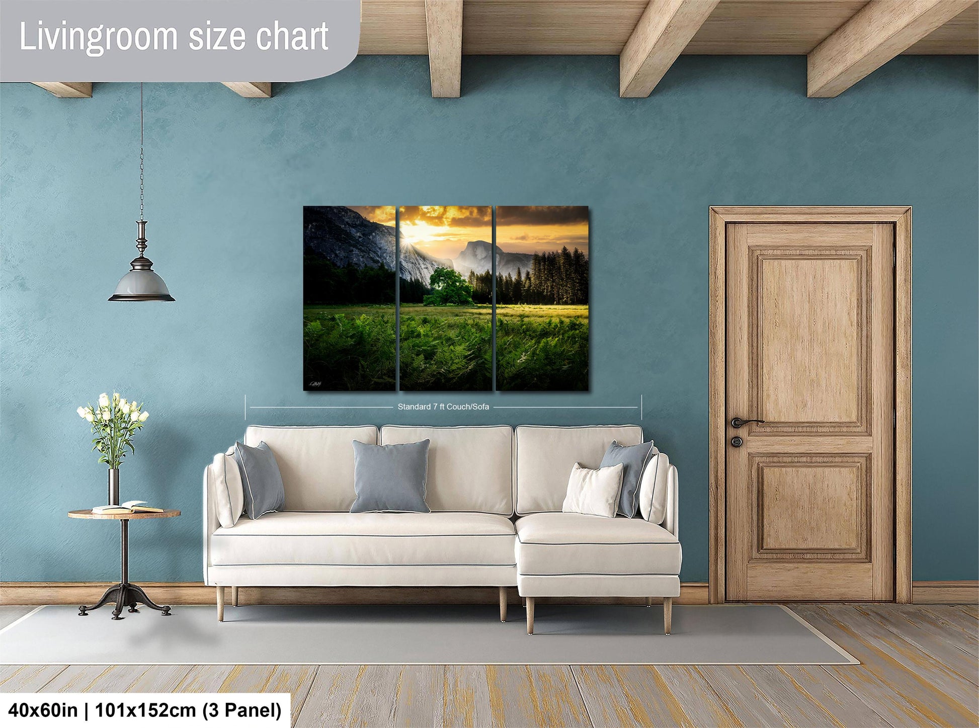 The image is a living room with a large, three-panel landscape painting hanging on the wall. The painting depicts a serene mountain landscape with a sunset. The room has a white sofa and a wooden door, creating a cozy and inviting atmosphere.