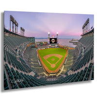 A panoramic view of a baseball stadium at dusk, with the field illuminated and the stands filled with spectators.
