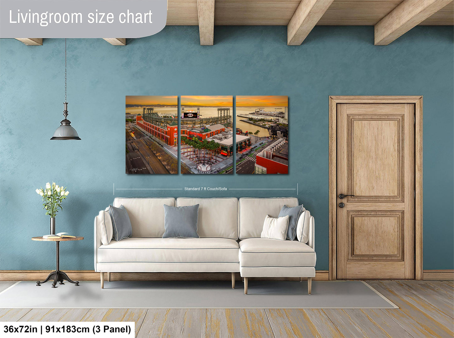 The image is a living room with a large, colorful, and detailed painting of a cityscape hanging on the wall. The painting is divided into three panels, and the living room has a white sofa, a wooden door, and a small table with a vase of flowers.