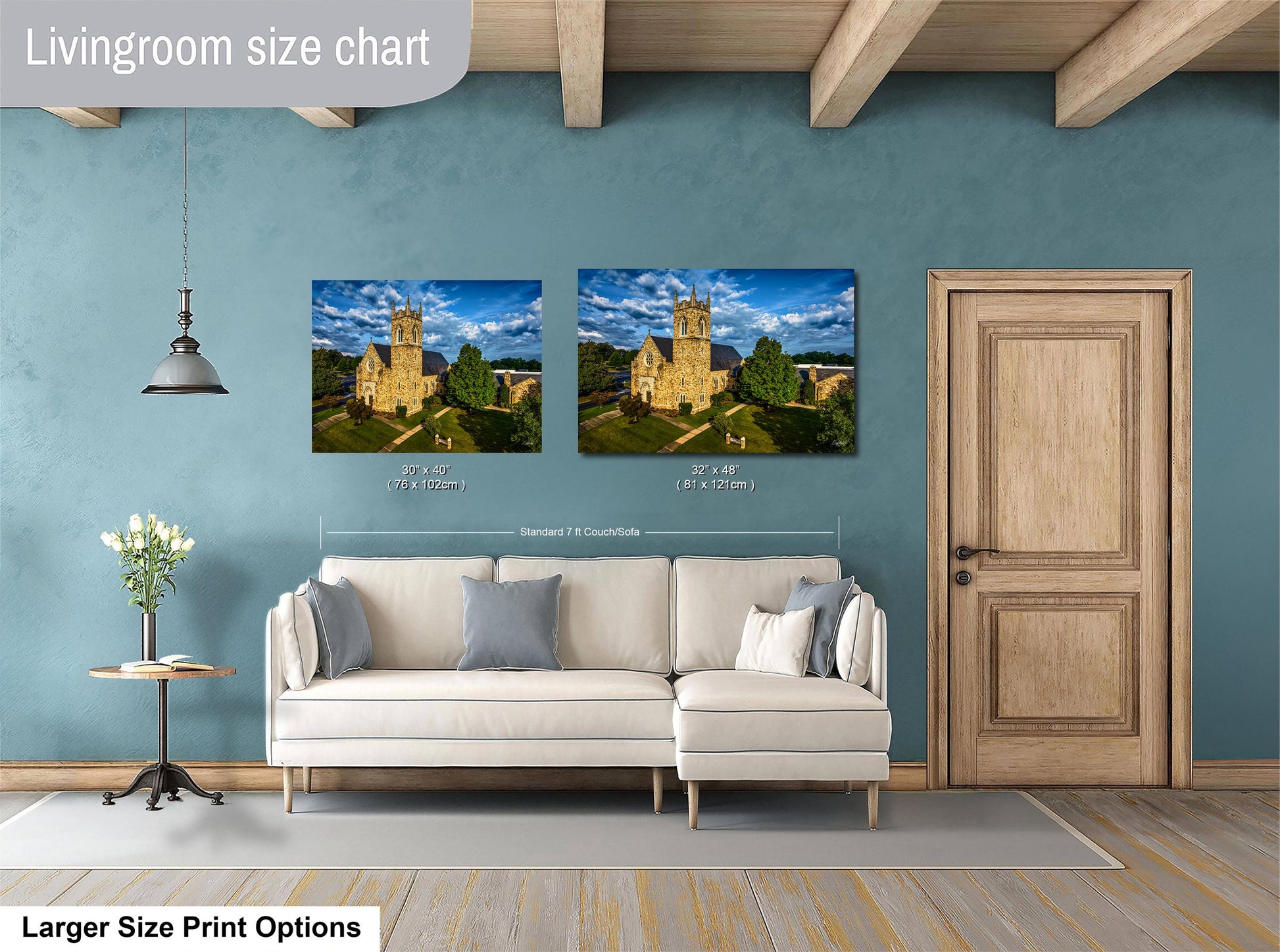 a living room with a white sofa and a wooden door. Above the sofa, there are two framed pictures of a castle, one larger than the other. The larger picture is approximately 30% wider than the smaller one. The living room has a blue wall and a wooden ceiling.