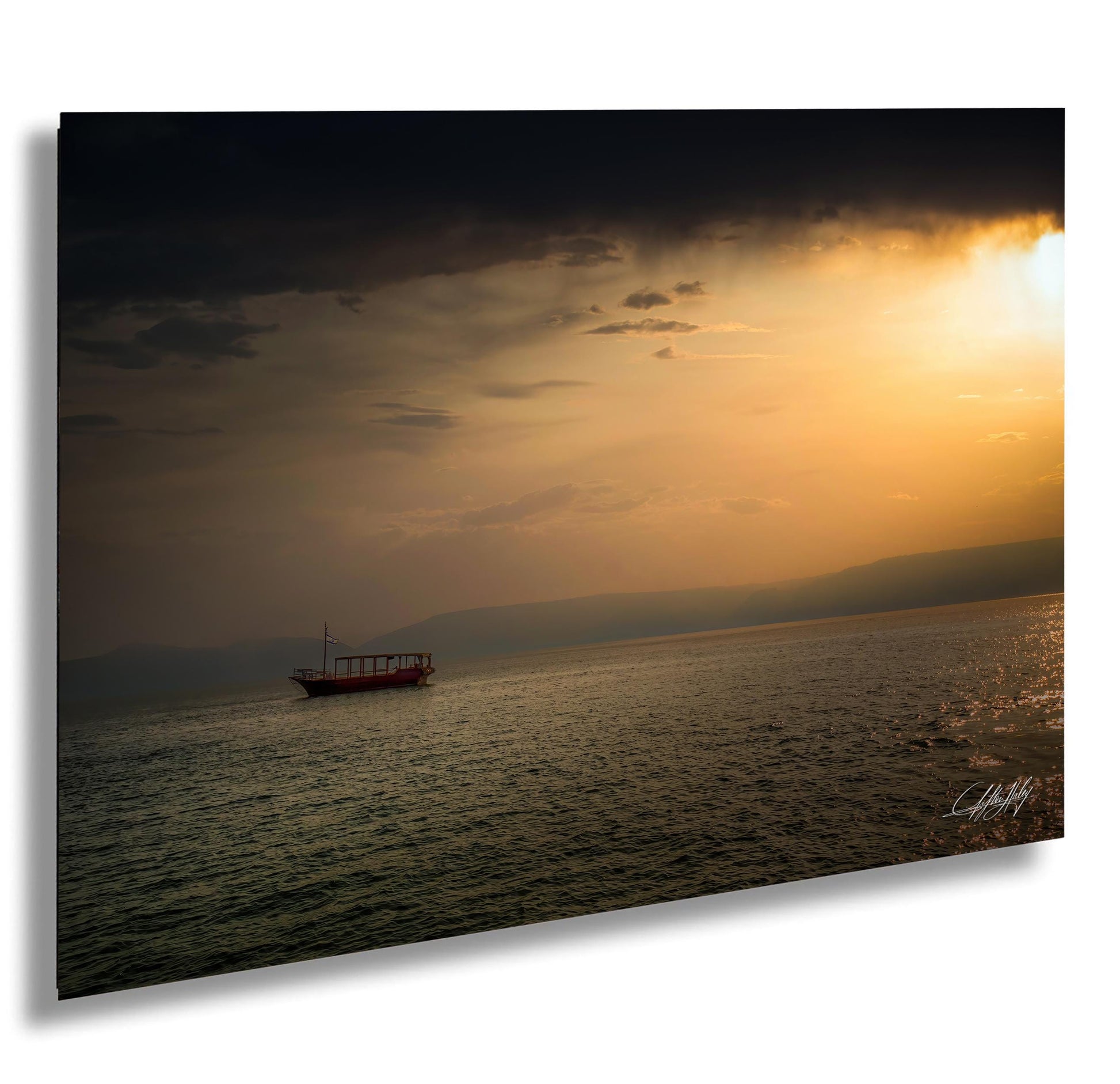 A lone boat sails across a calm body of water, with a dramatic sunset sky in the background.