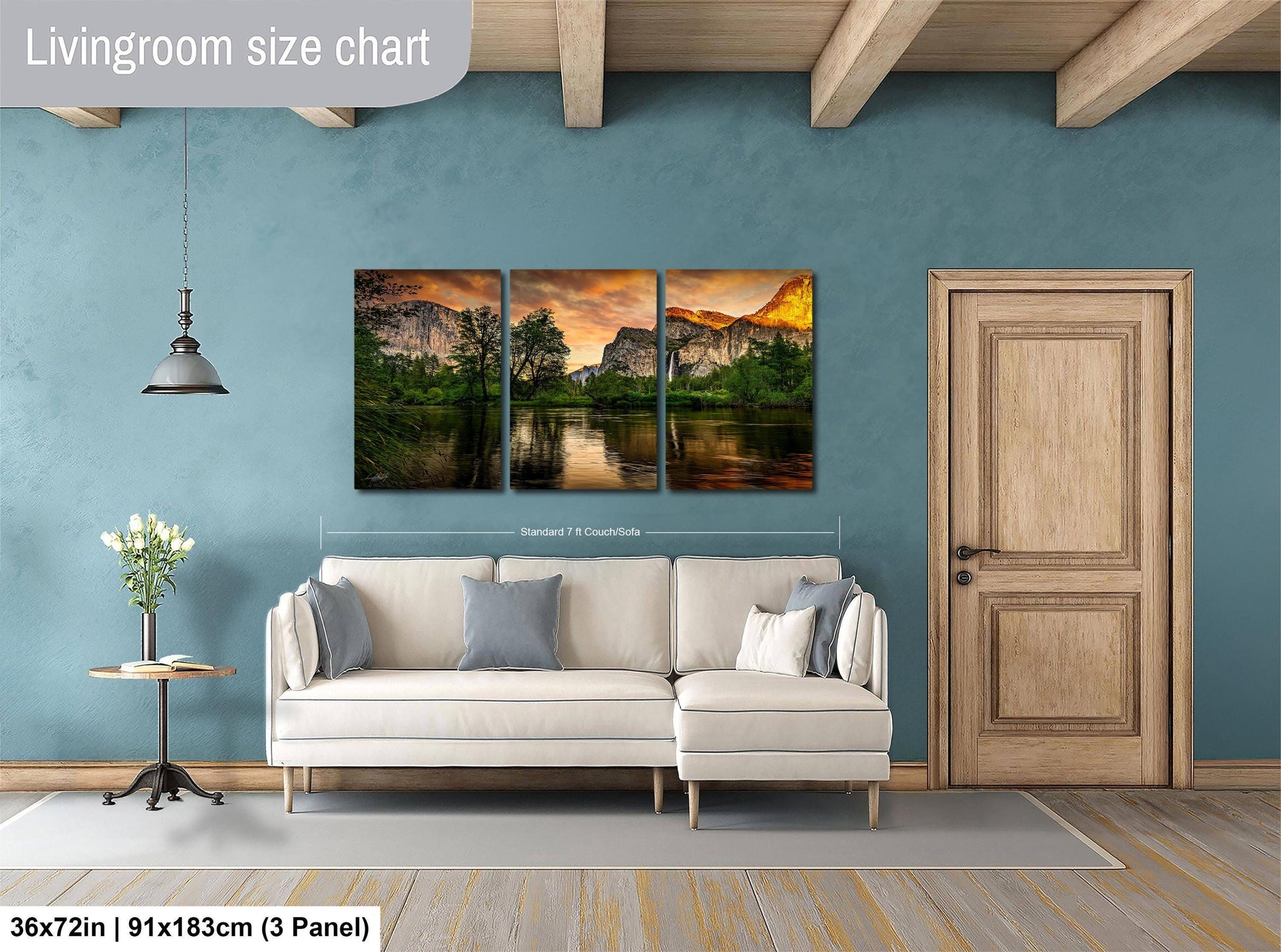 The image is a living room with a large wall art depicting a scenic landscape with mountains and a lake. The living room has a white sofa and a wooden door, and the wall art is approximately 36 inches wide and 15 inches tall.