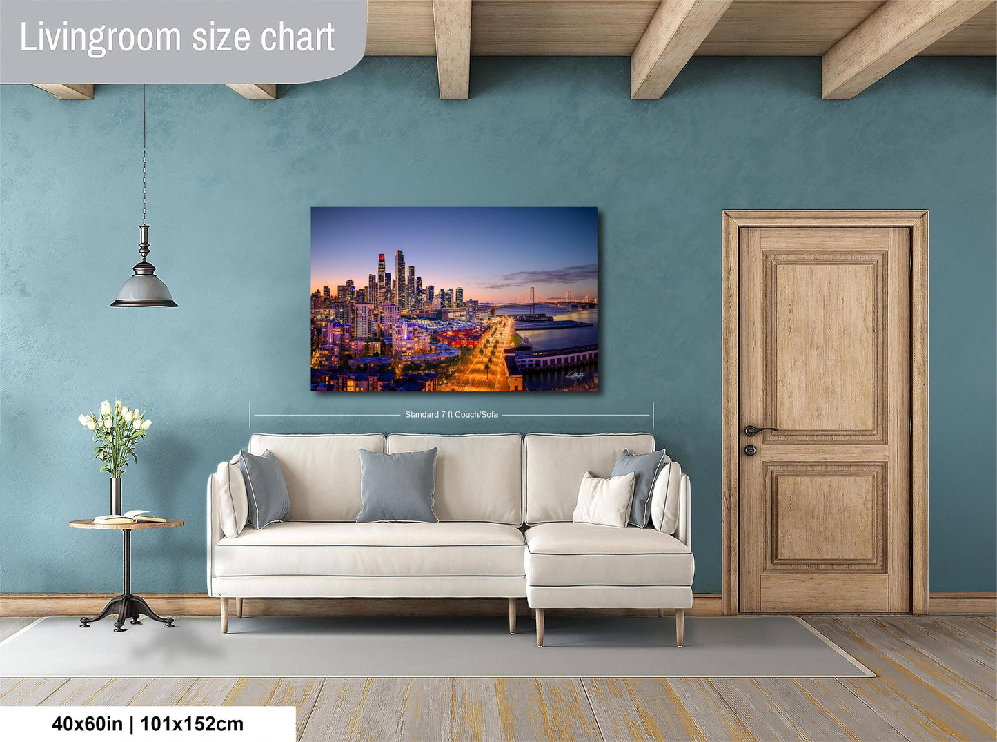 a living room with a large city skyline painting hanging on the wall. The painting is framed and measures 40 inches by 101.5 centimeters. The room has a white sofa and a wooden door, creating a cozy and modern atmosphere.