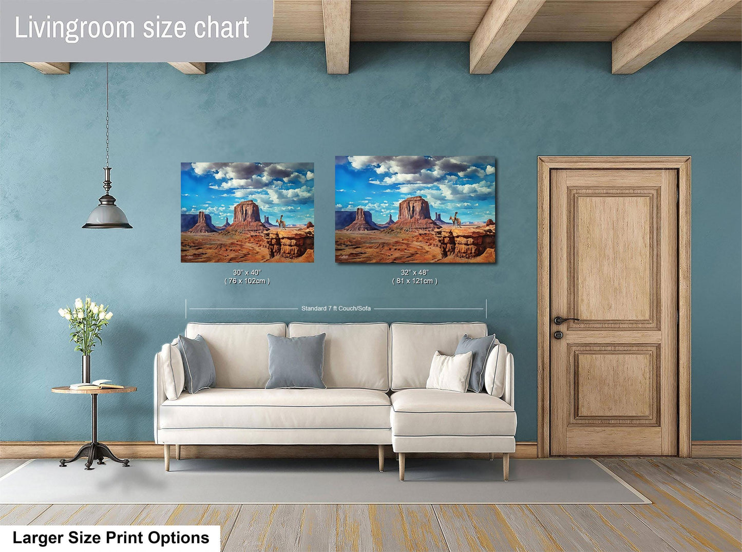 a living room with a white sofa and a wooden door. Above the sofa, there are two framed pictures of desert landscapes, likely depicting Monument Valley. The living room has a blue wall and a wooden ceiling.