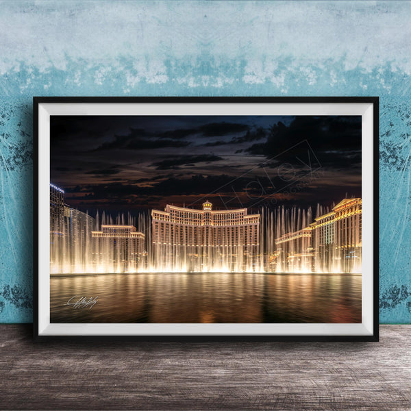 A framed photograph of the Bellagio Fountains in Las Vegas at night, with the fountains illuminated and creating a stunning reflection on the water surface.