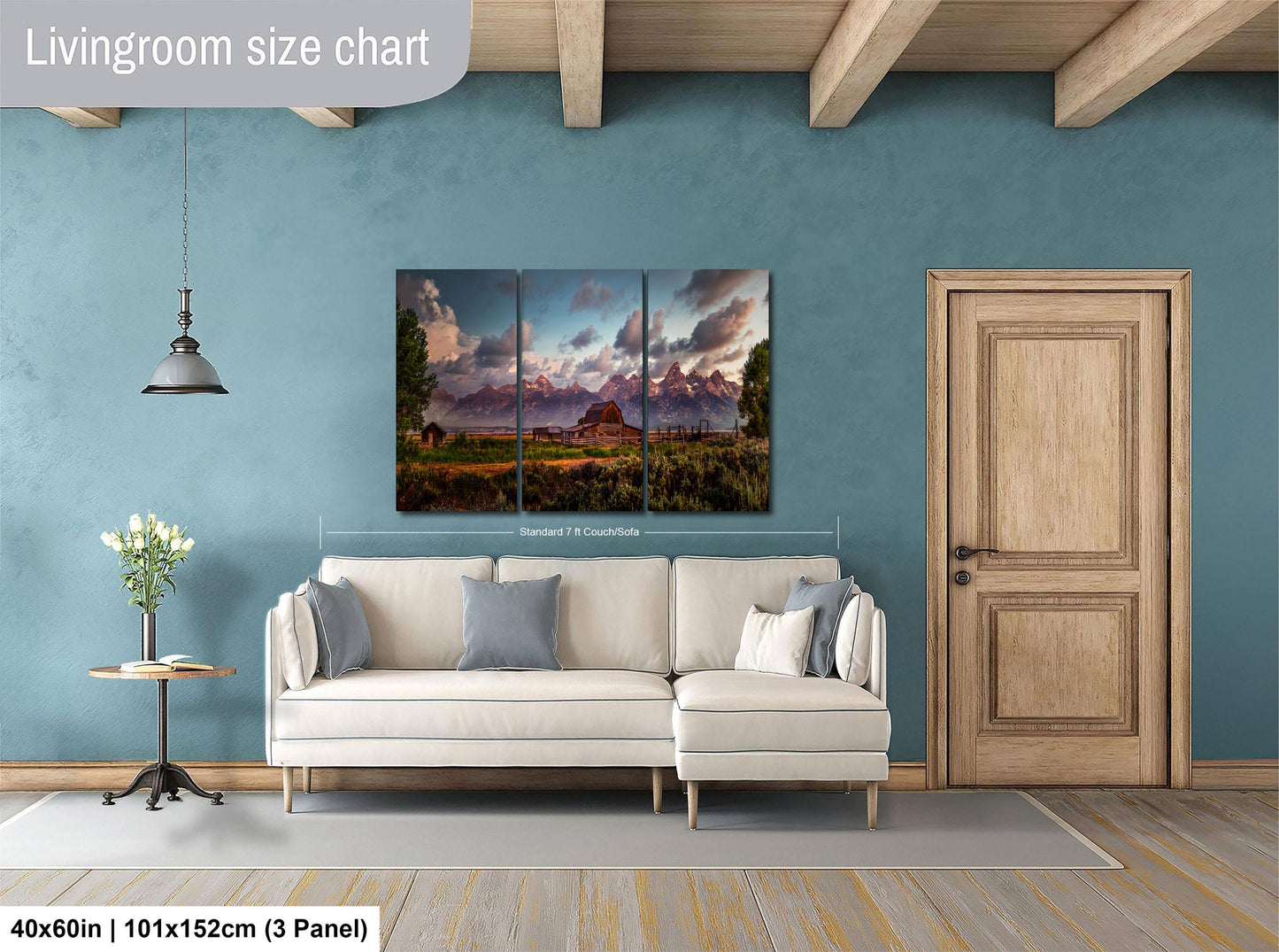 The image is a living room with a large painting of a mountain landscape hanging on the wall. The painting is divided into three panels, and the living room has a white sofa, a wooden door, and a small table with a vase of flowers.