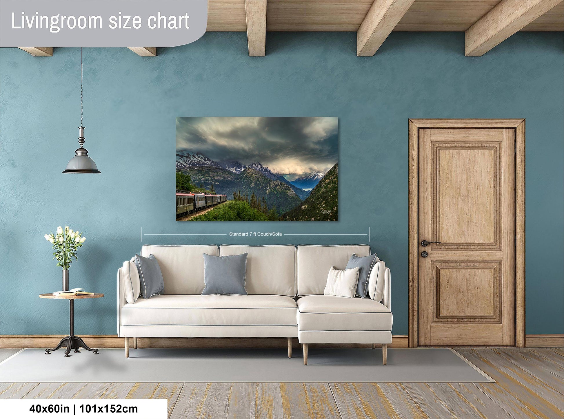 a living room with a large landscape painting hanging on the wall. The painting features a mountainous scene with a train passing through the valley. The room has a white sofa and a wooden door, creating a cozy and inviting atmosphere.
