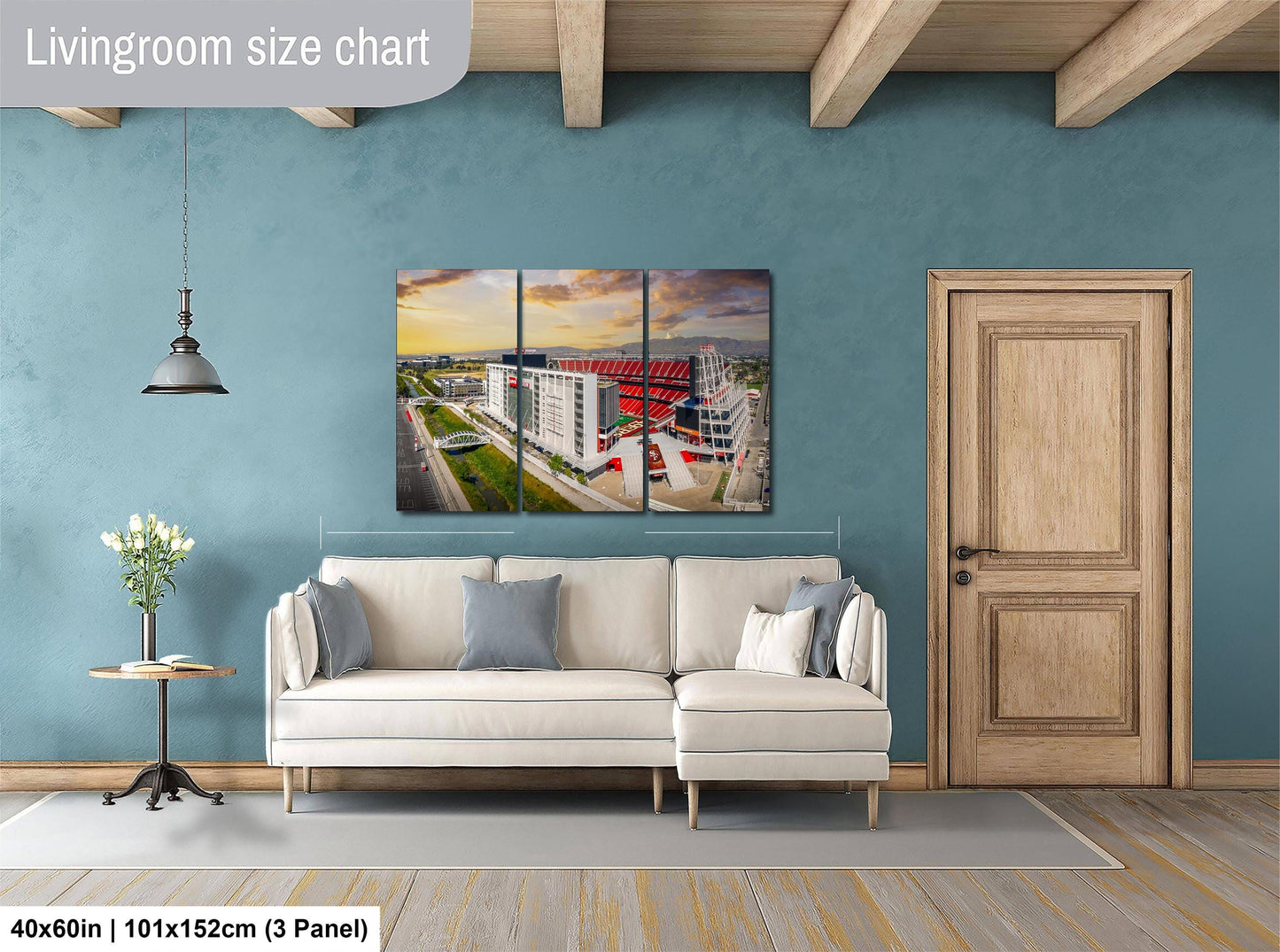 The image is a living room with a white sofa, a wooden door, and a large wall art depicting a cityscape.