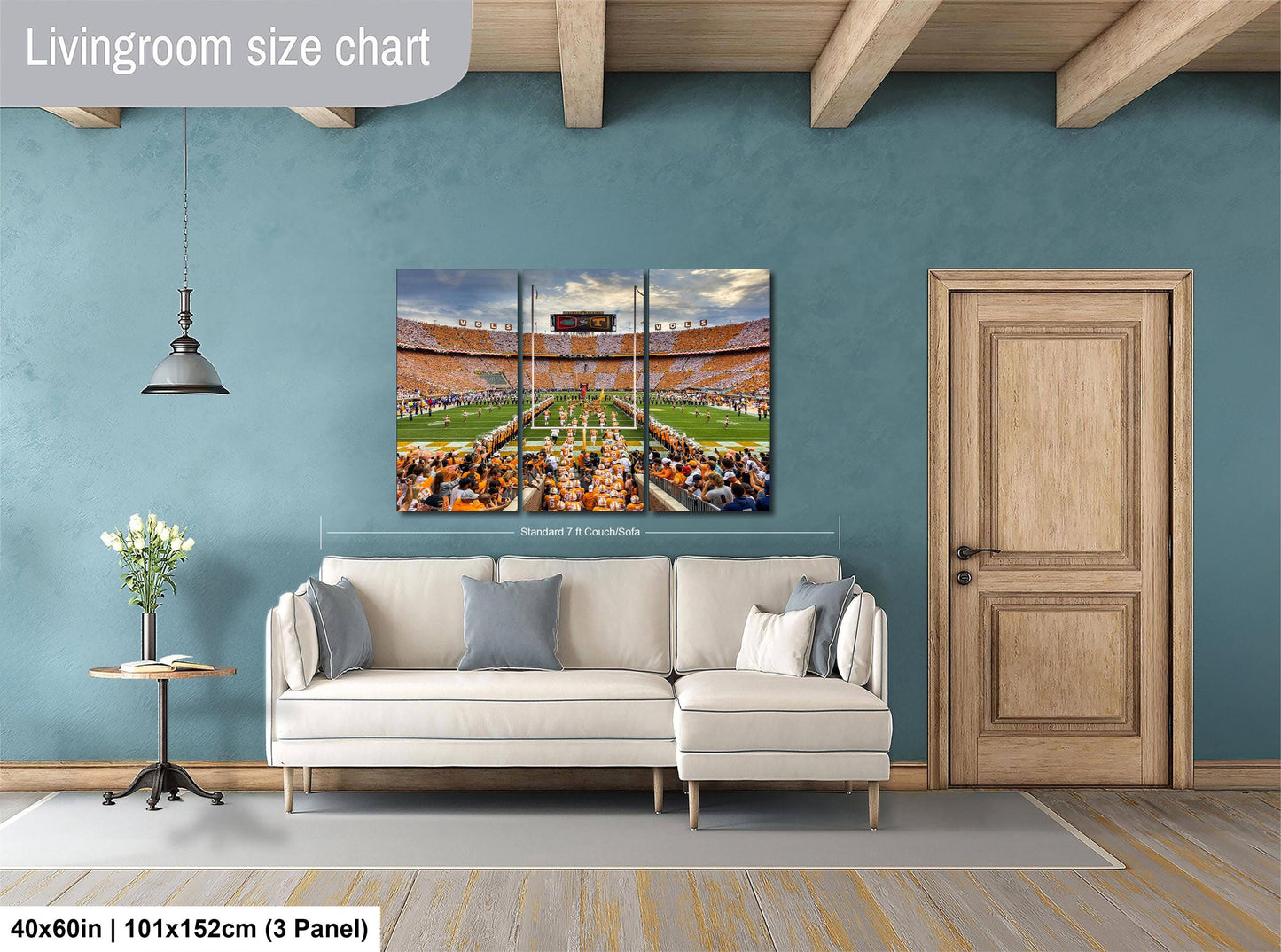 The image is a living room with a large white sofa, a wooden door, and a painting of a stadium on the wall.