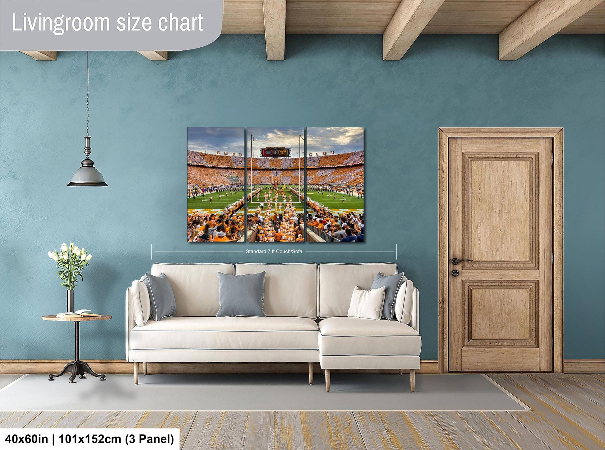 The image is a living room with a large white sofa, a wooden door, and a painting of a stadium on the wall.