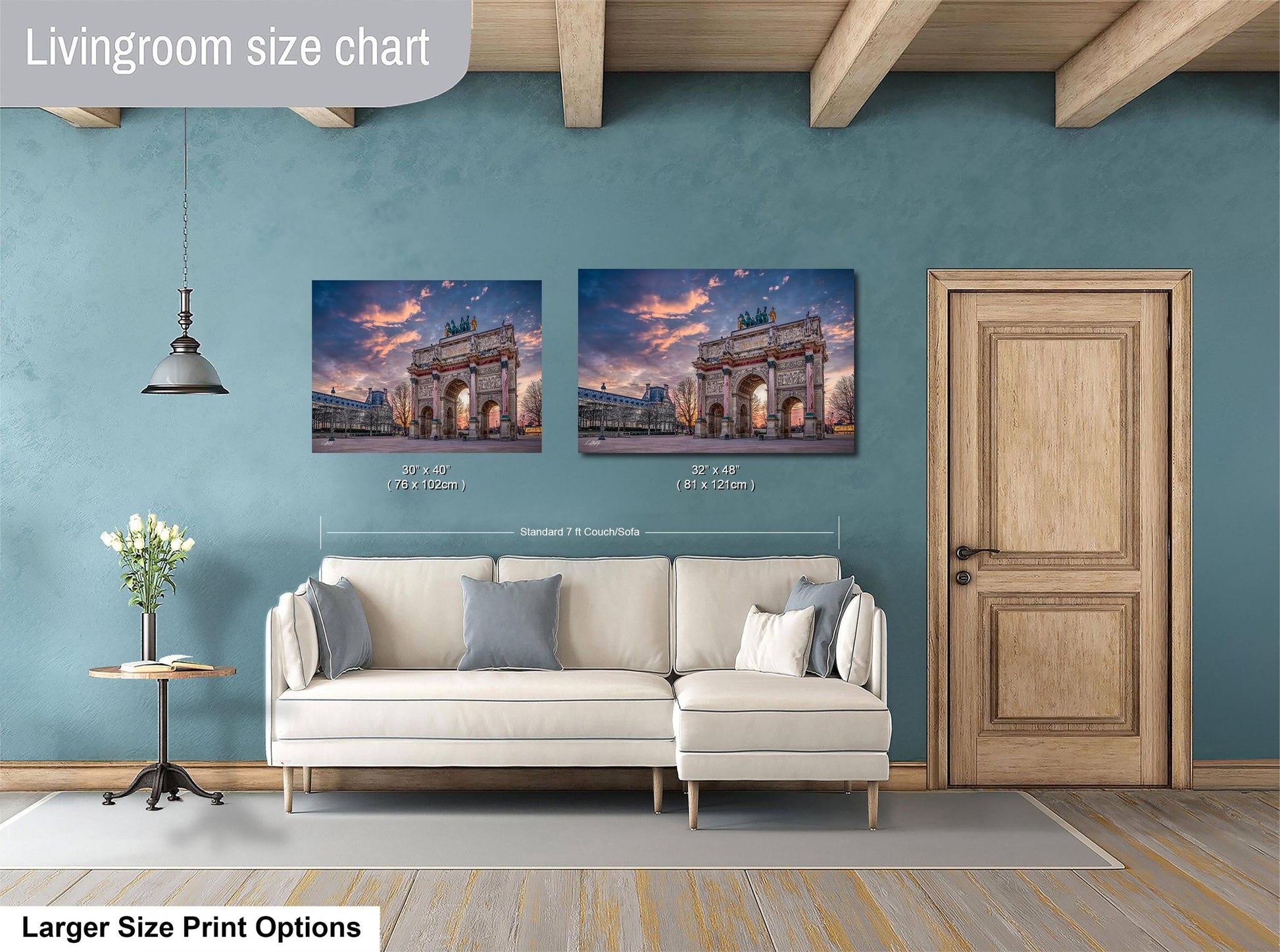 a living room with a white sofa and a wooden door. Above the sofa, there are two framed pictures of a building, likely a historical or architectural landmark. The sofa is positioned in front of the pictures, creating a focal point in the room. The living room appears to be well-lit and decorated, with a potted plant and a vase adding to the overall aesthetic.